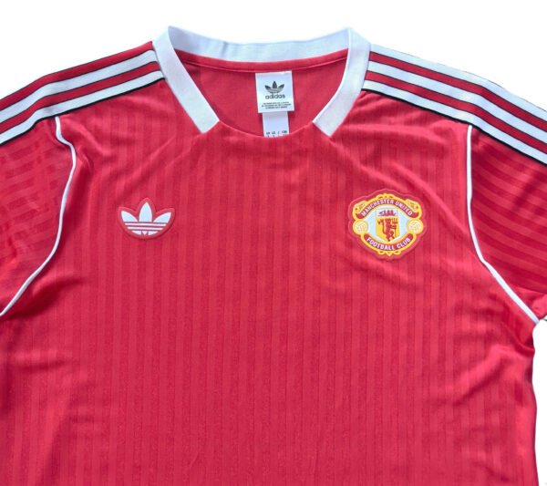 Manchester United third jersey 2025/26, red with white accents and club crest.