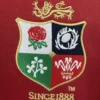Embroidered sports patch featuring a crest with a lion, rose, and other symbols on red fabric backgr.