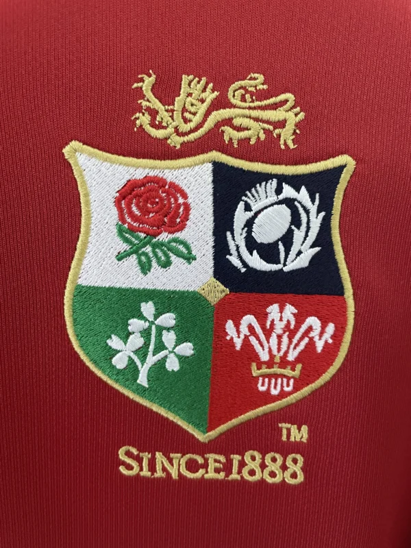 Embroidered sports patch featuring a crest with a lion, rose, and other symbols on red fabric backgr.