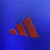 Sportswear logo on blue fabric background. Adidas logo embroidered on athletic clothing or gear.
