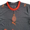 AC Milan Soccer Jersey with Puma Logo and Team Badge AC Milan football jersey featuring Puma logo and team badge, black with red accents.