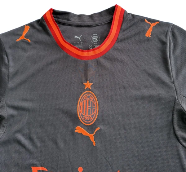 AC Milan Soccer Jersey with Puma Logo and Team Badge AC Milan football jersey featuring Puma logo and team badge, black with red accents.