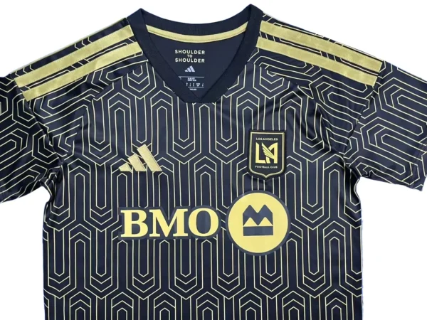 Football jersey with BMO logo and geometric pattern, black and gold design. Football jersey with BMO logo, geometric pattern, and gold accents for sports fans.