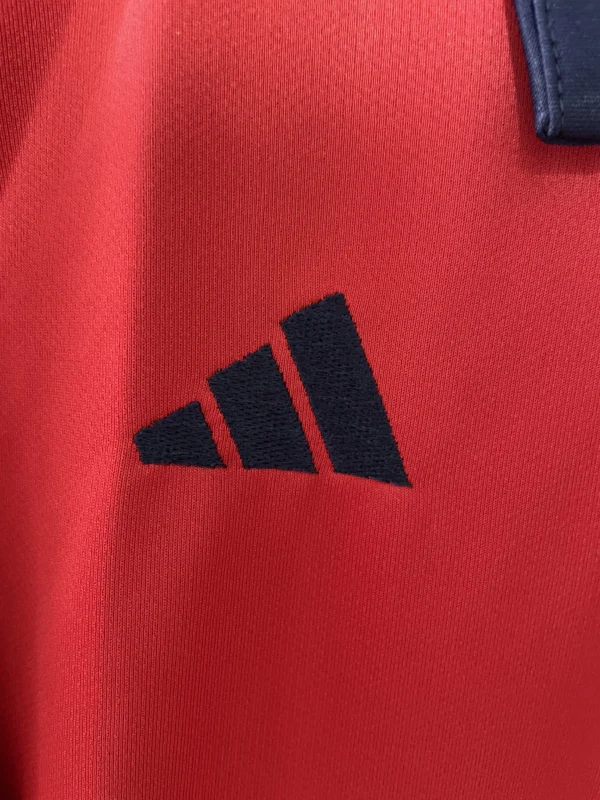 Close-up of Adidas logo on red athletic sportswear fabric.