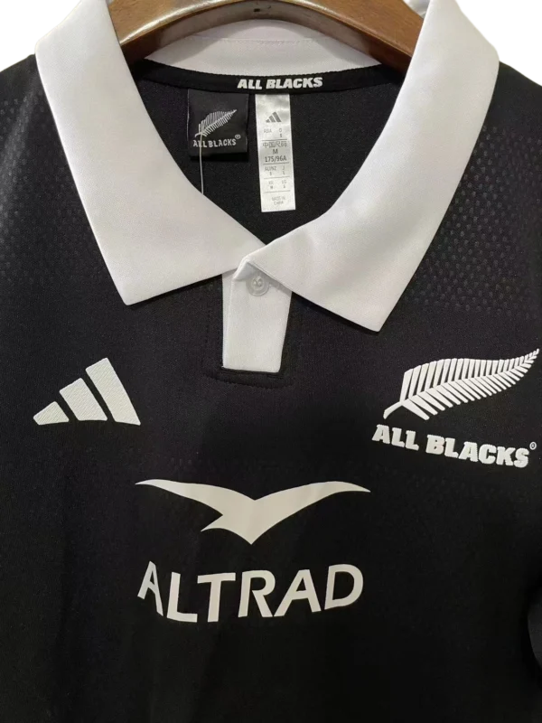All Blacks Rugby Jersey for Men Black All Blacks rugby jersey with white collar and sponsor logos, ideal for sports enthusiasts.