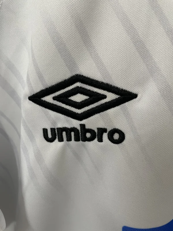 Umbro logo embroidered on white sports jersey fabric, showcasing athletic apparel branding.